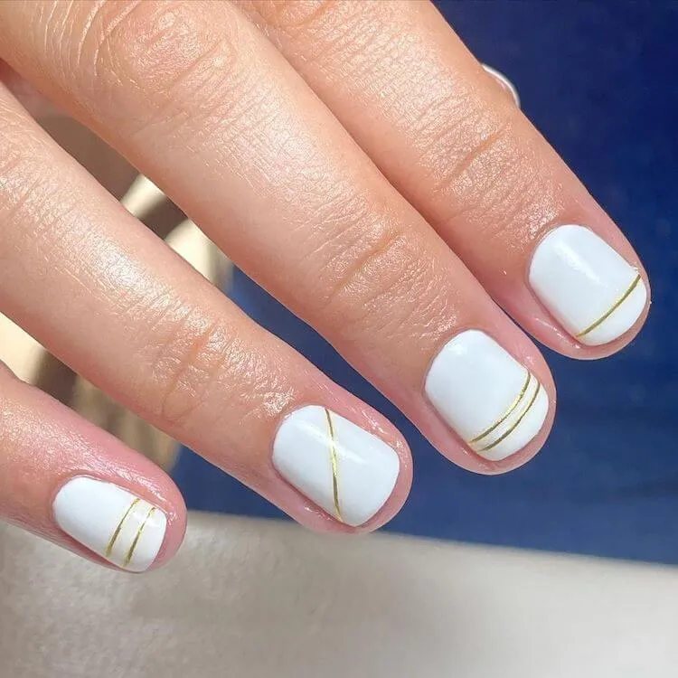 vita naglar med guldfärgade ränder
